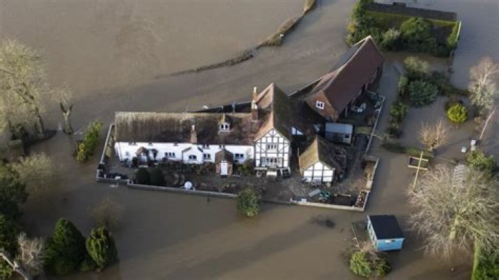Modern-day 'King Canute' builds 7ft flood wall protecting £600k home as aerial pics show dry garden surrounded by water